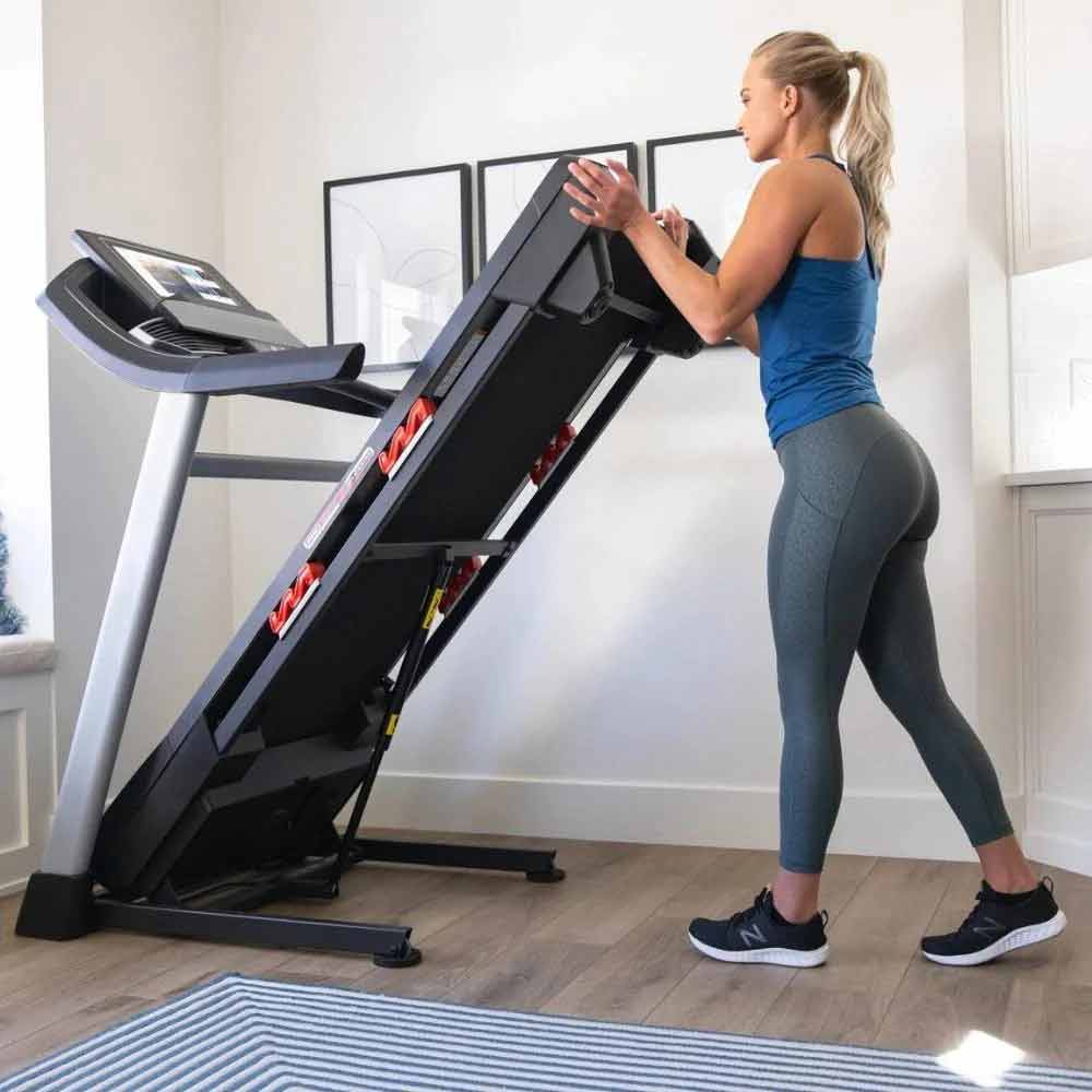 Proform Trainer 14 Treadmill side view being folded by woman